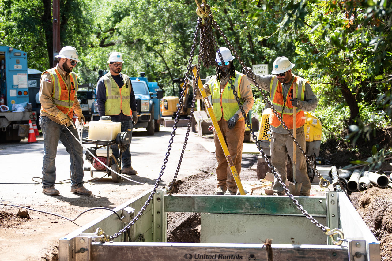 Work crew dressed in a vest and hard hat looking at undergrounding eqiupment.