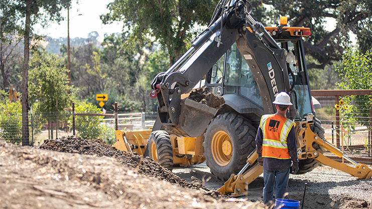 A worker standing in front of a construction vehicle.