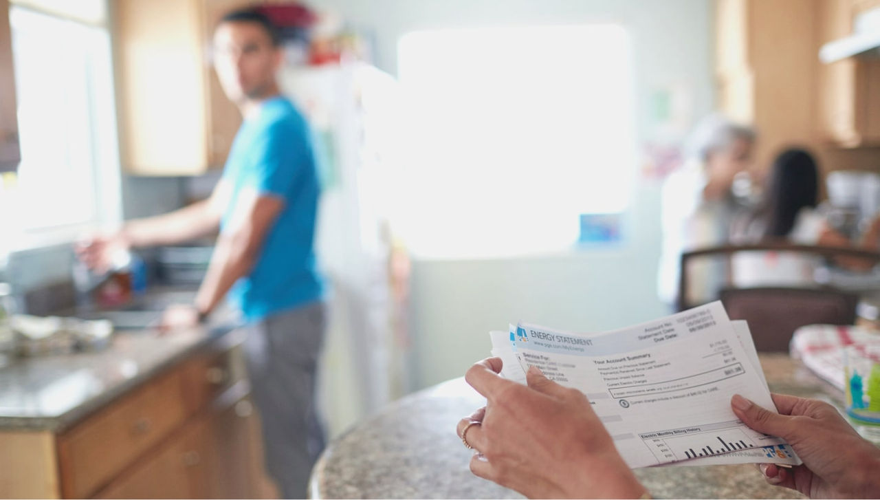 Una persona mira su factura de PG&E en una cocina