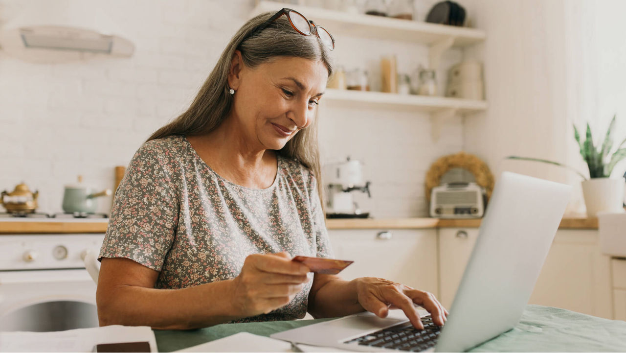 A person holding a credit card and typing on a computer.